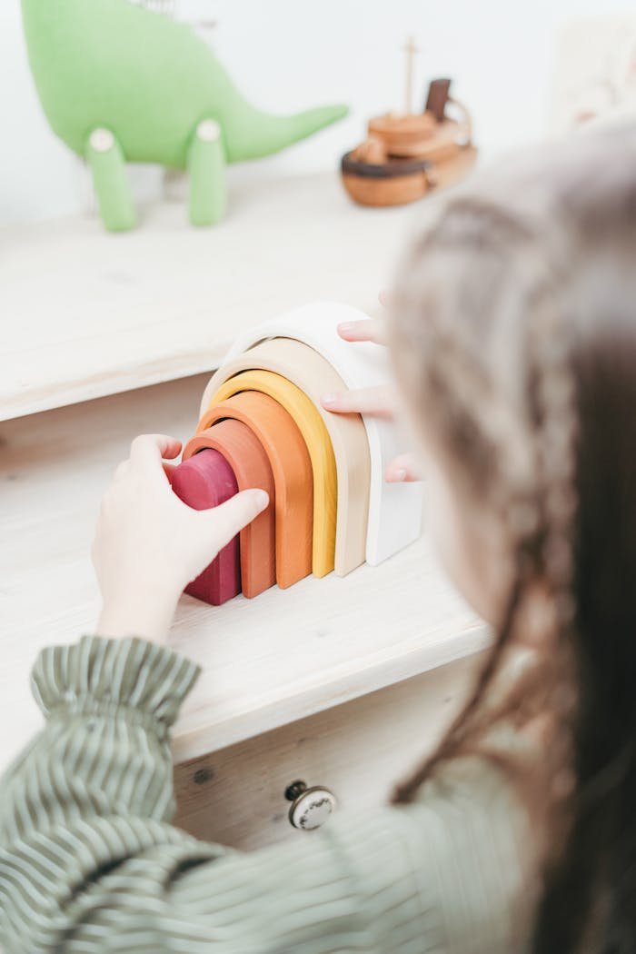 A child engaging in creative play with rainbow-colored wooden toys on a desk.